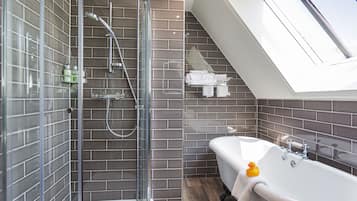A modern bathroom with a glass-enclosed shower, a freestanding bathtub, and a skylight.