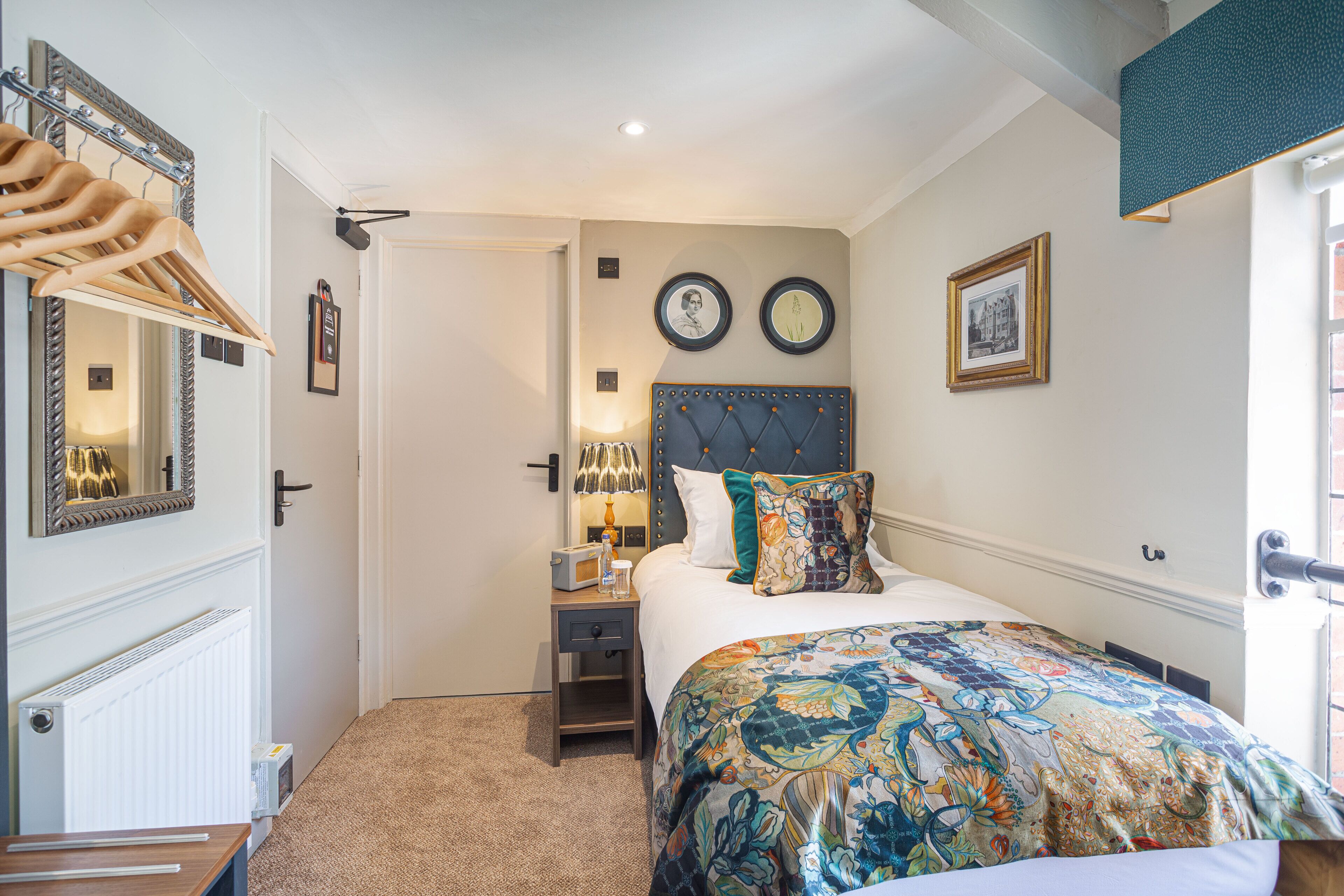 A bedroom with a bed, a nightstand, a mirror, and a door.