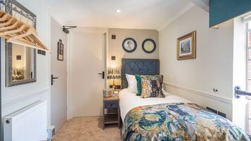 A bedroom with a bed, a nightstand, a mirror, and a door.