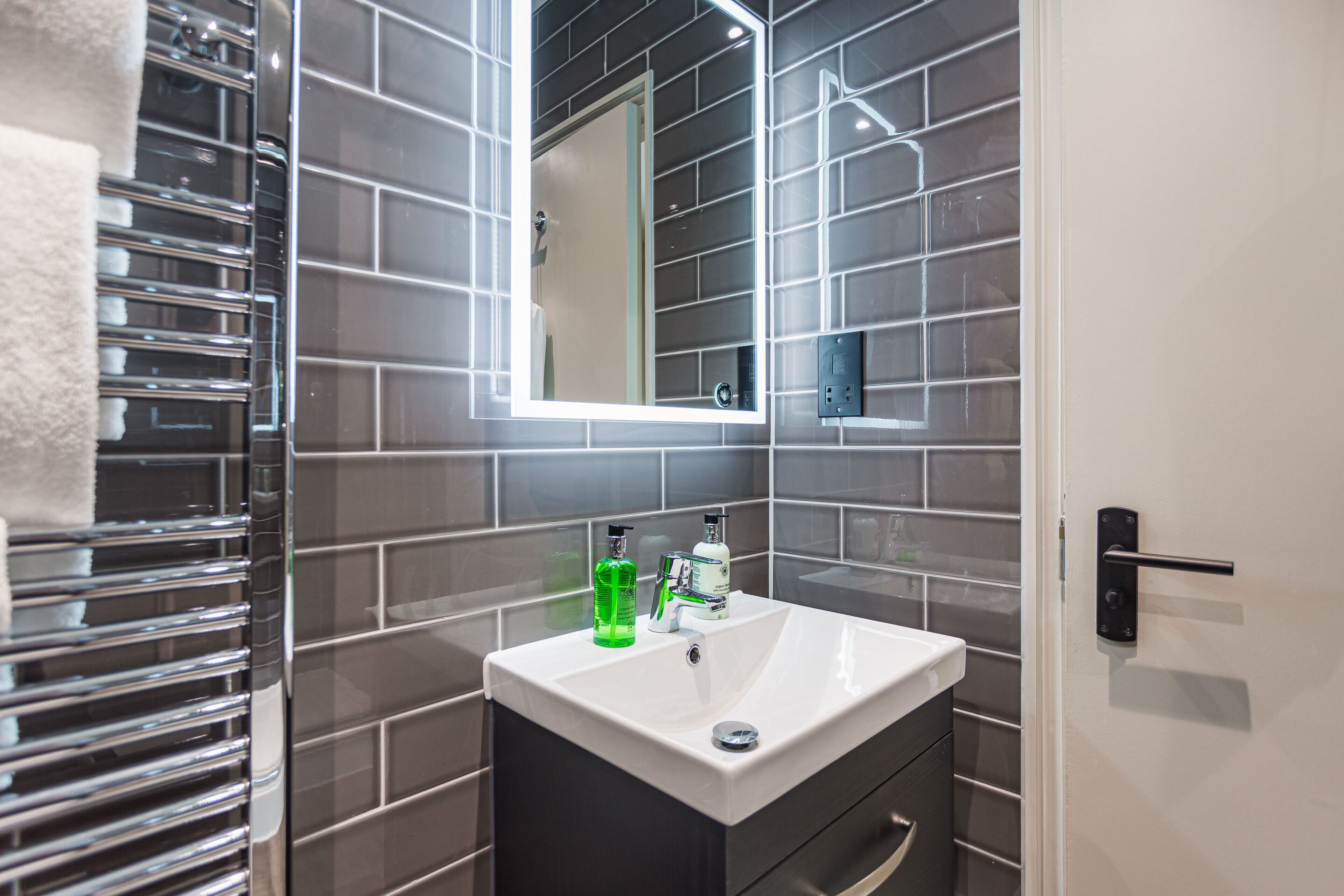 A modern bathroom with a white sink, a mirror, and a towel rack.