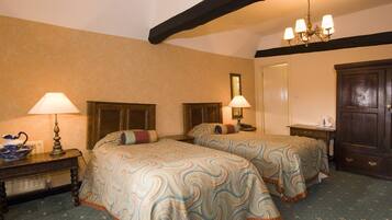 Una habitación de hotel con dos camas, una mesita de noche con lámpara, un aparador y un candelabro.