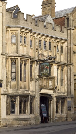 Ein historisches Gebäude mit einem Schild für das 'The George & Pilgrim's Hotel' und einer Illustration eines Ritters aus dem Mittelalter.
