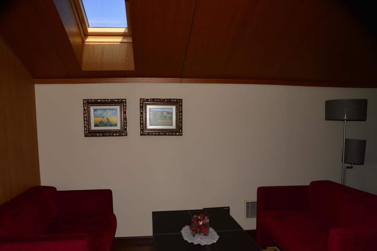 Una habitación con dos sofás rojos, una mesa de centro negra con un objeto decorativo y dos cuadros en la pared.