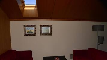 A room with two red sofas, a black coffee table with a decorative item, and two framed pictures on the wall.