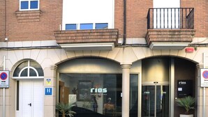A hotel entrance with a glass facade, a wheelchair-accessible entrance, and a sign indicating a hotel.