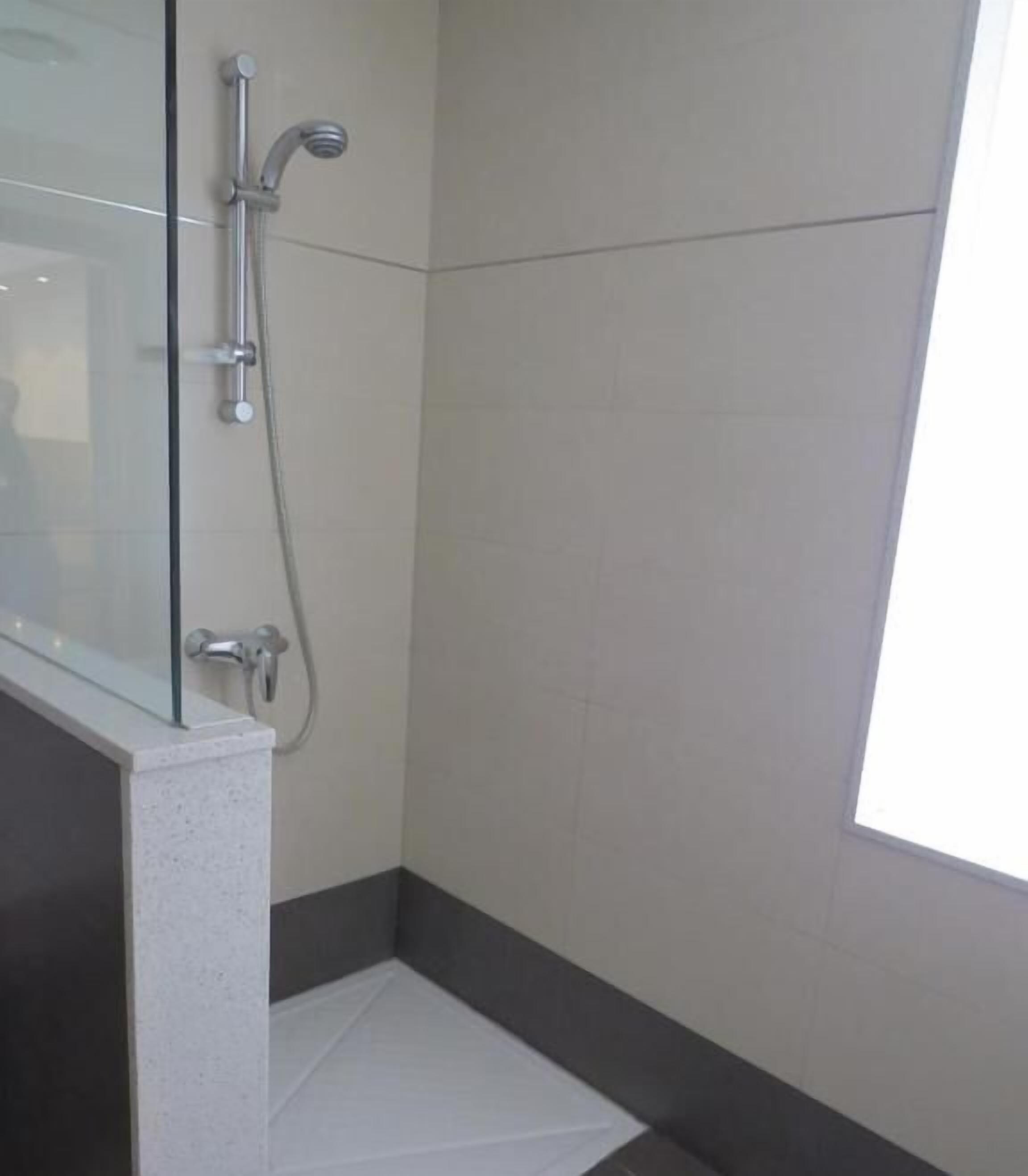Une petite salle de bain moderne avec une douche à parois de verre, des murs carrelés et un sol foncé.