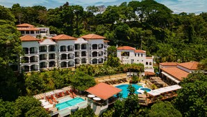 A resort with multiple buildings, a swimming pool, and lush greenery. - Shana by the Beach Manuel Antonio (Quepos)