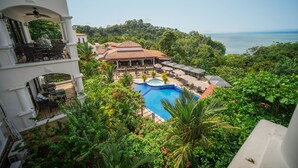 A resort with a swimming pool surrounded by lush greenery and a view of the sea. - Shana by the Beach Manuel Antonio (Quepos)