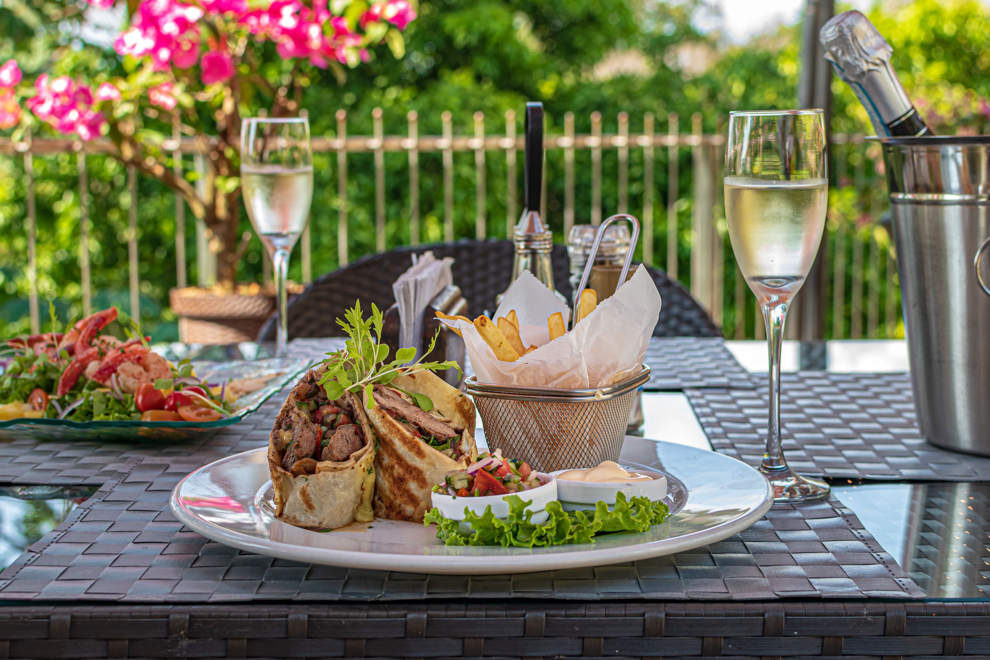A dining table with a plate of food, a drink, and a basket of fries.