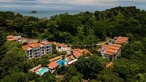 Een resort met meerdere gebouwen, een zwembad en weelderige begroeiing rondom.