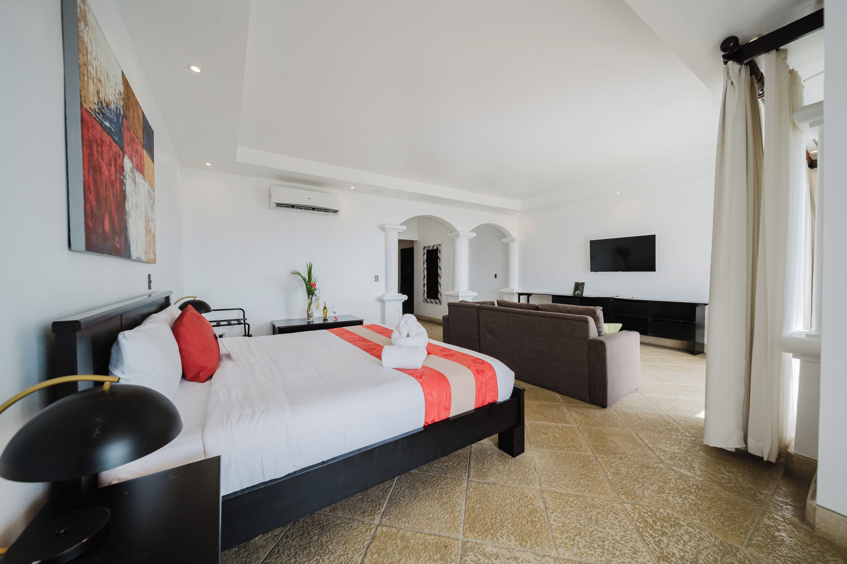 Una camera d'albergo con un letto, una televisione, un divano e un'area pranzo.