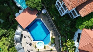 Luchtbeeld van een resort met een zwembad, ligbedden en een kleine ronde hottub.