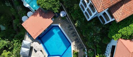 Oversigtsbillede af et resort med swimmingpool, liggestole og et lille rundt spabad.