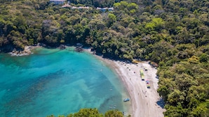 A coastal area with a beach, clear turquoise waters, and dense forested hills. - Shana by the Beach Manuel Antonio (Quepos)