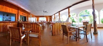 Un restaurante espacioso con mobiliario de madera y una zona de bar.