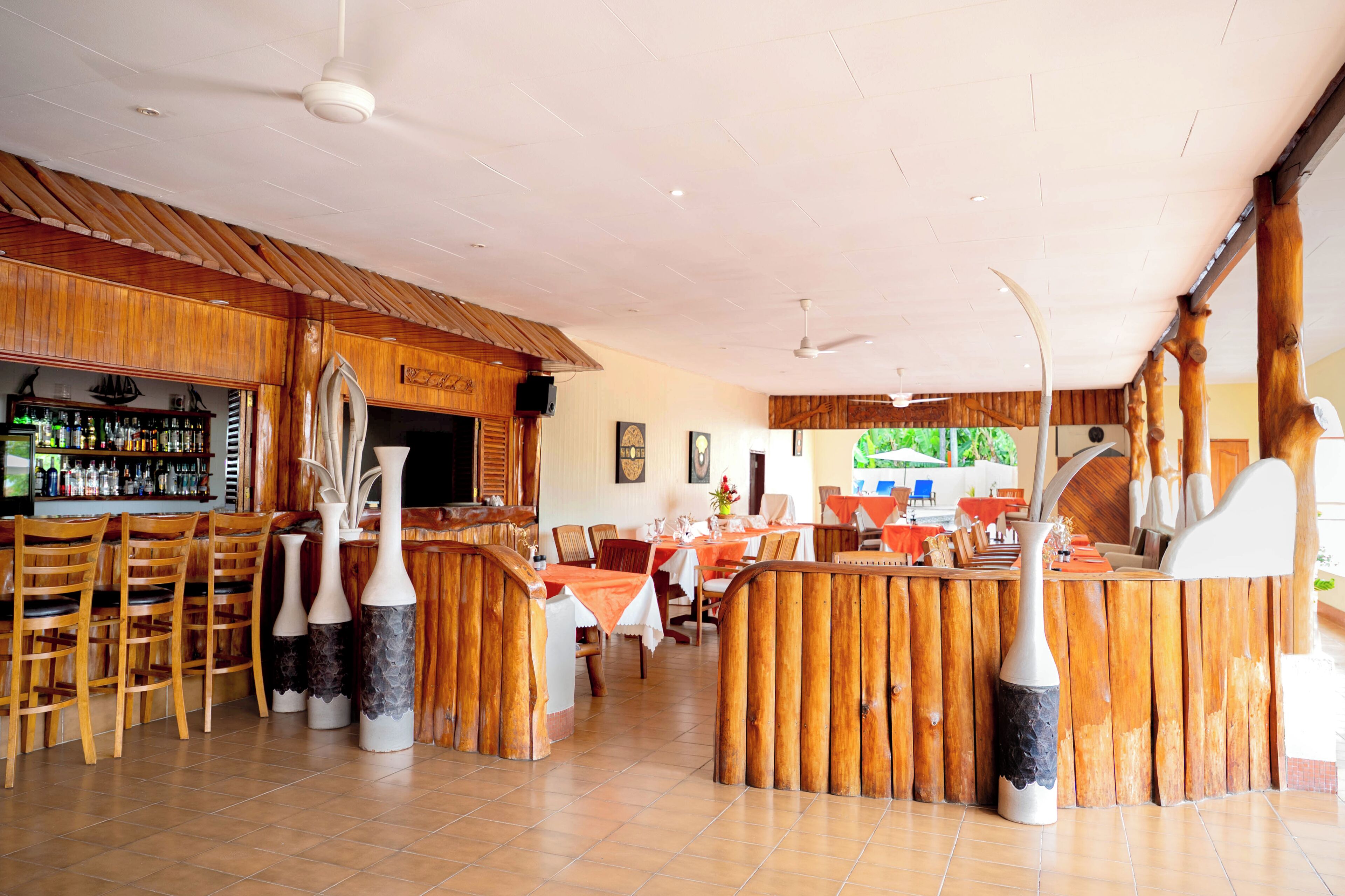 Un restaurante con mobiliario de madera, una zona de bar y una sección de comedor.