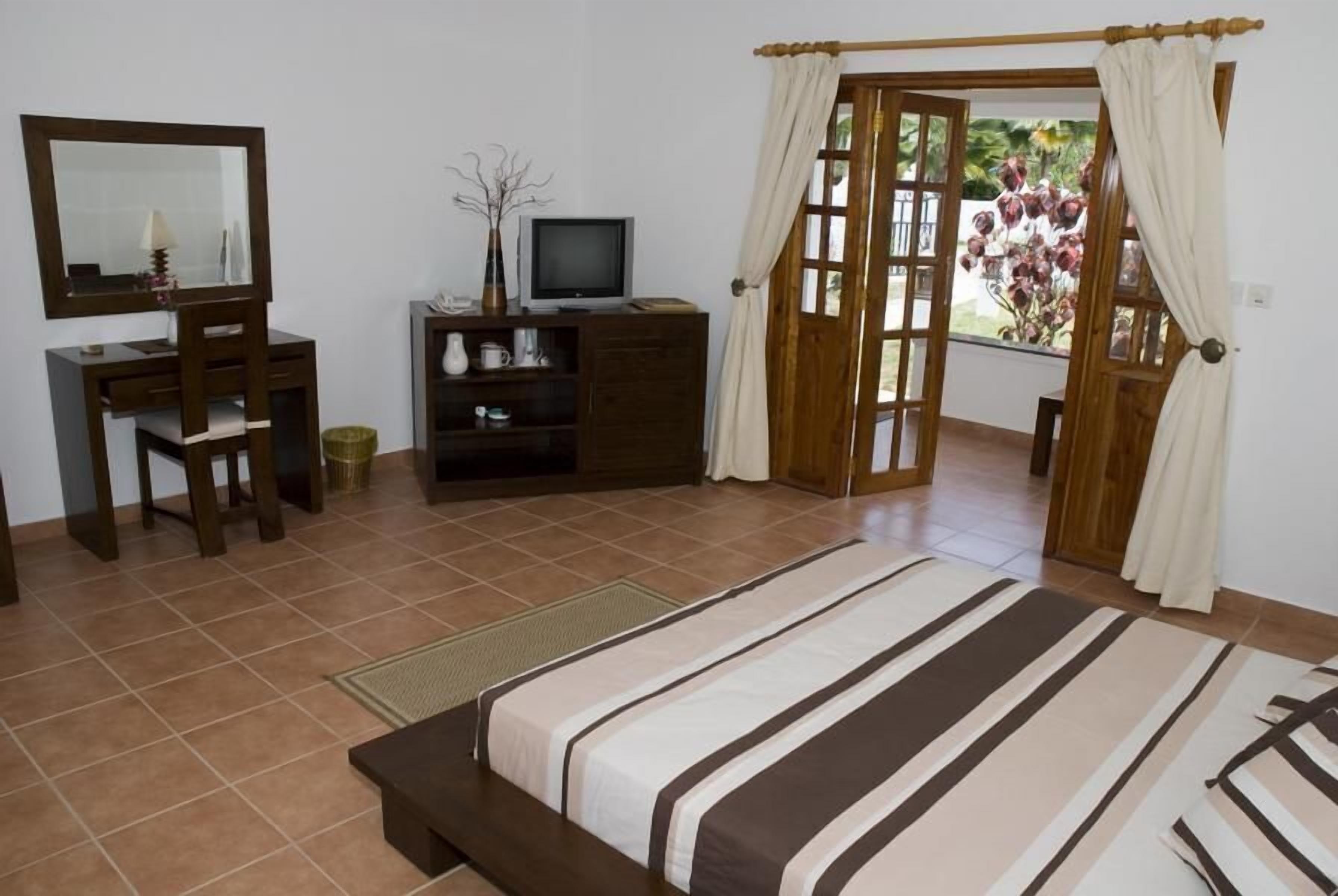 A bedroom with a bed, a desk, a television, and a wardrobe.