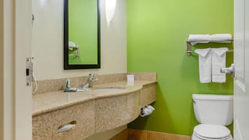 Un baño con lavamanos de encimera de granito, un espejo, un inodoro y un perchero para toallas.