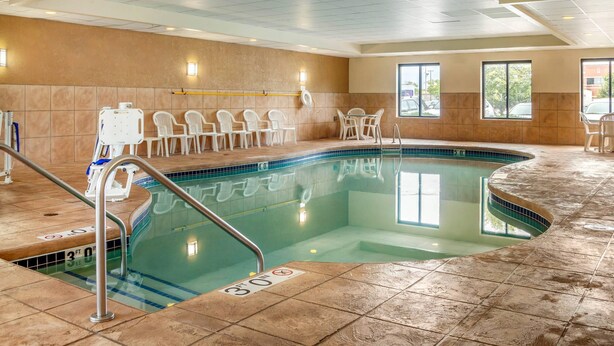 Una piscina con bordo piastrellato, una sedia per il bagnino e un ombrellone.