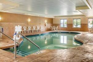 A swimming pool with a tiled deck, a lifeguard chair, and a sunshade.