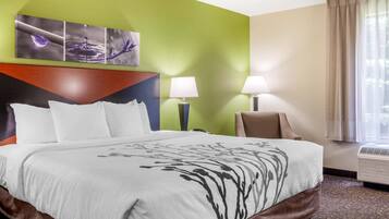 A hotel room with a large bed, two bedside lamps, a green accent wall, and a window with curtains.