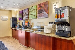 A hotel breakfast area with a coffee machine, a water dispenser, and a sign for 'moming Medley Breakfast'.