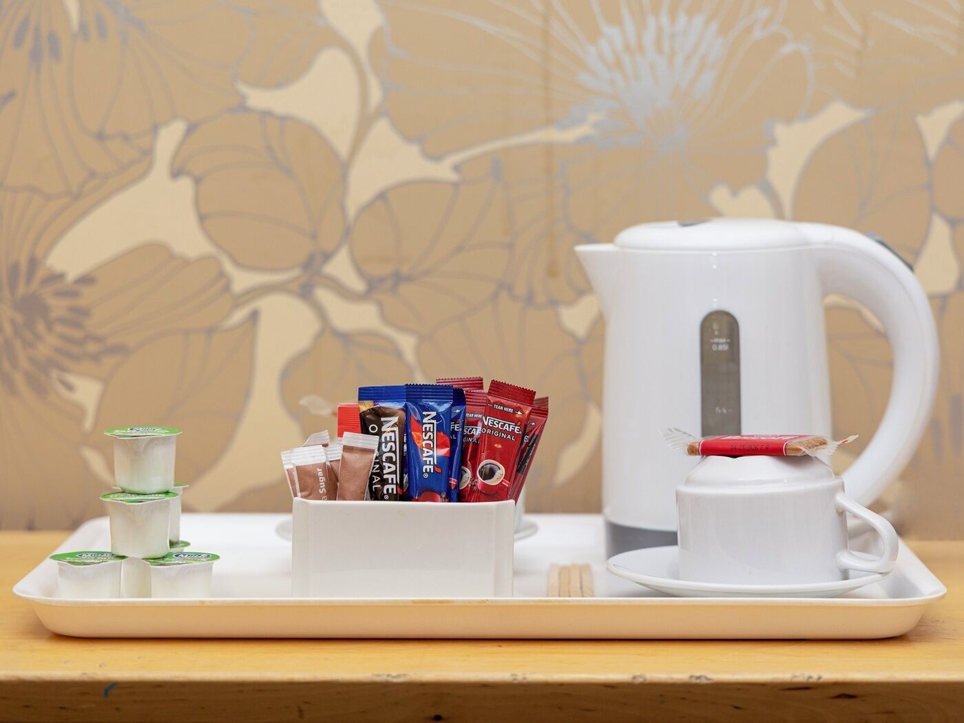 A tray with a coffee maker, a cup, and a stack of coffee pods.