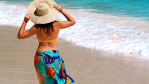 Una persona caminando sobre la playa con sombrero.