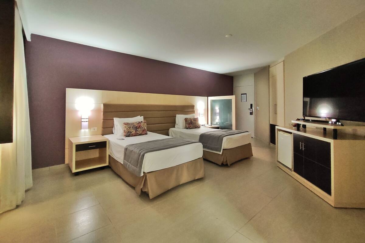 A hotel room with two beds, a TV, and a minibar.