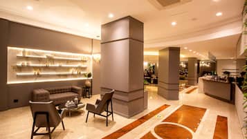 A modern lobby with a sofa, chairs, a reception desk, and a marble floor.