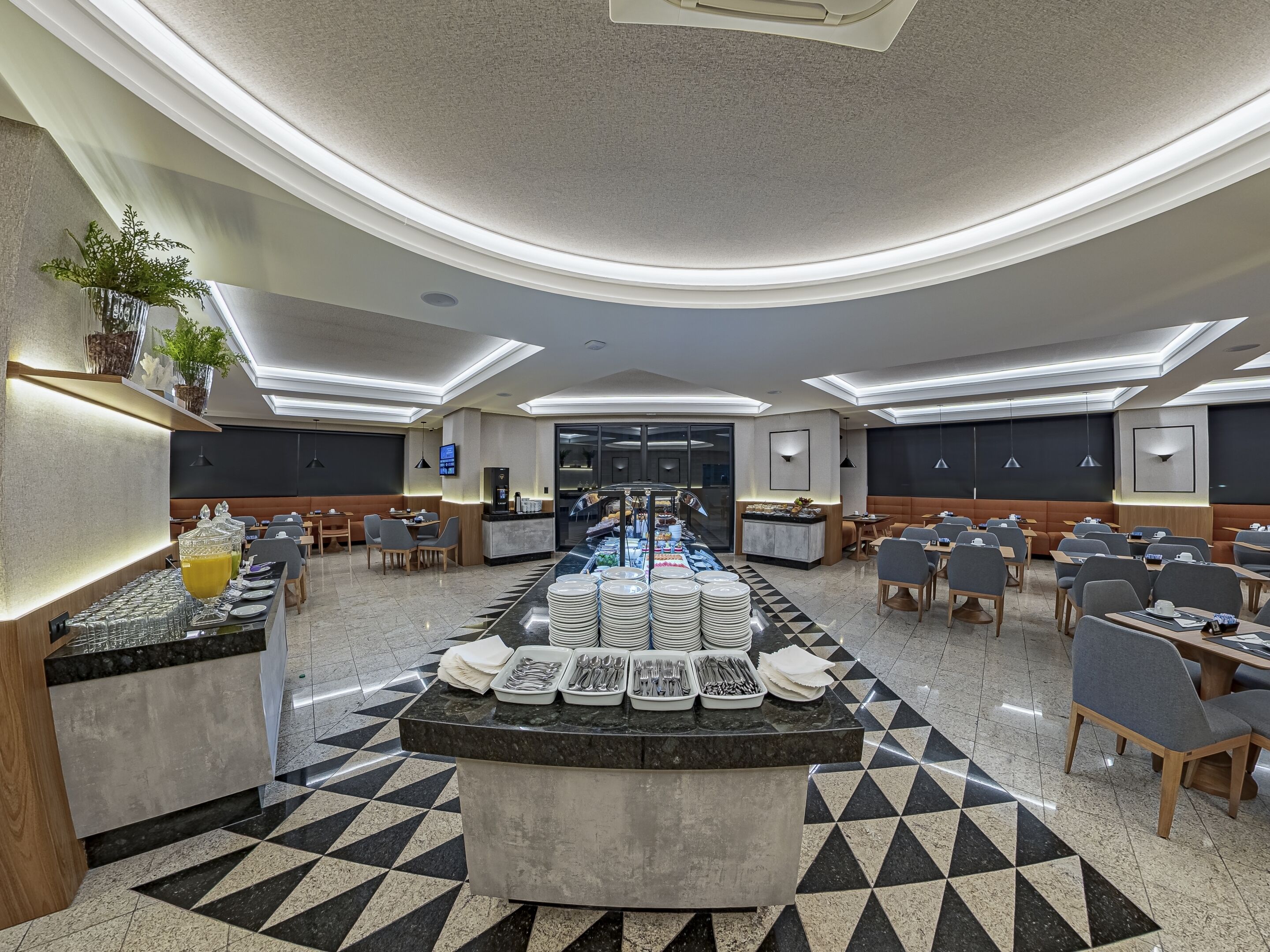 Een moderne hotellobby met een centraal buffetgedeelte, zithoekjes en een receptiebalie.