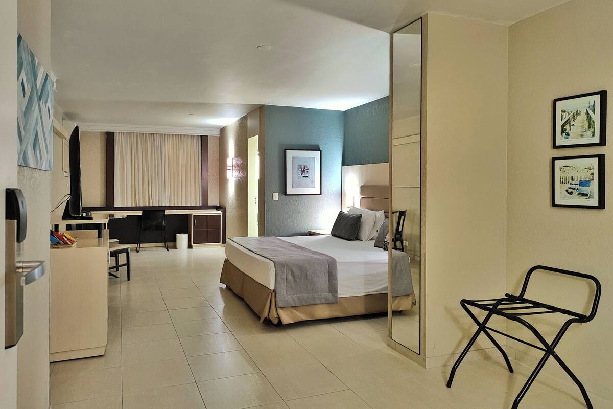 A hotel room with a bed, a desk, a chair, and a television.