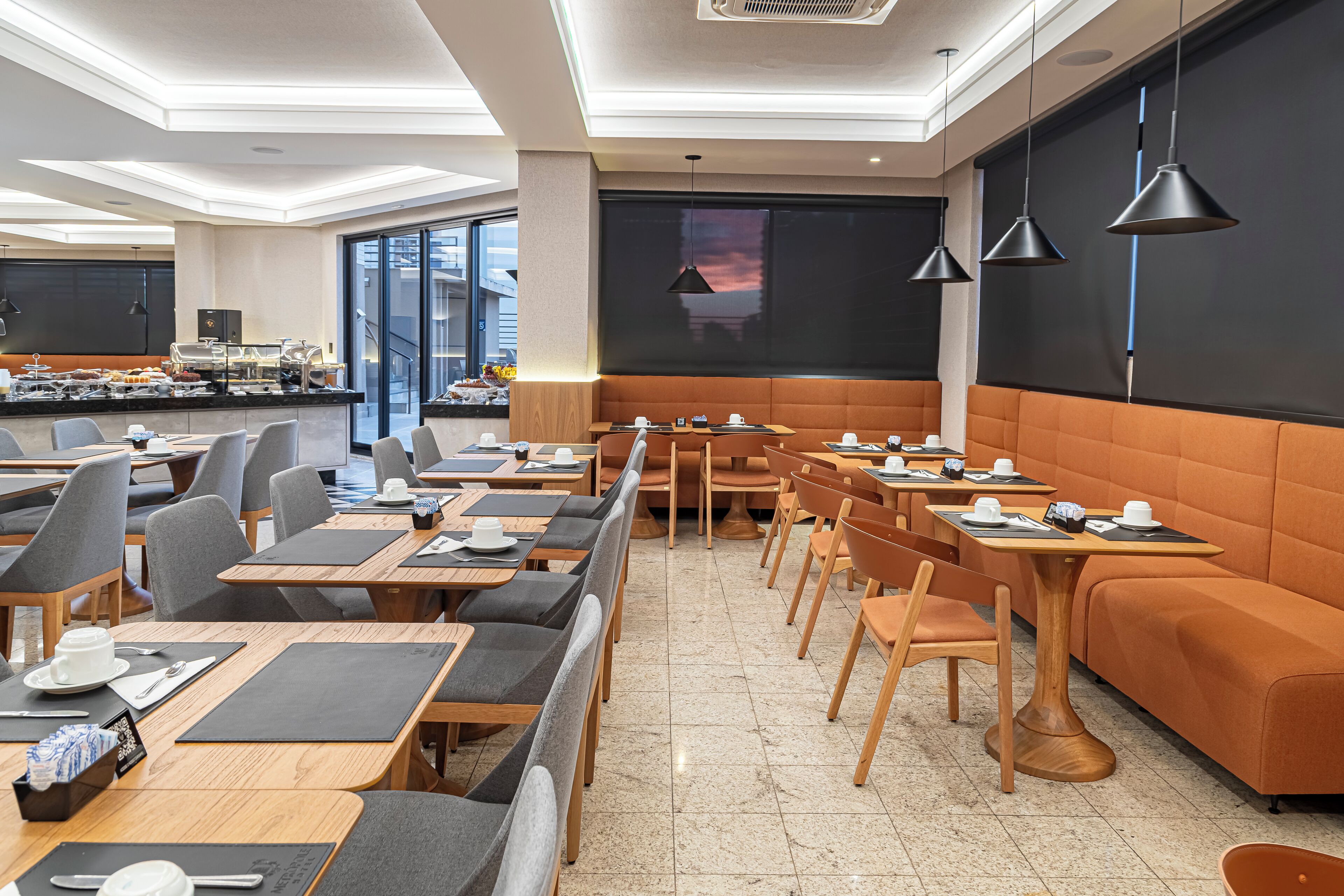 A modern dining area with tables and chairs, a buffet, and a large window with a view.