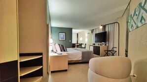 A hotel room with a bed, a desk, a chair, a TV, and a dining area. - Hotel Metrópole Maringá (Maringá)