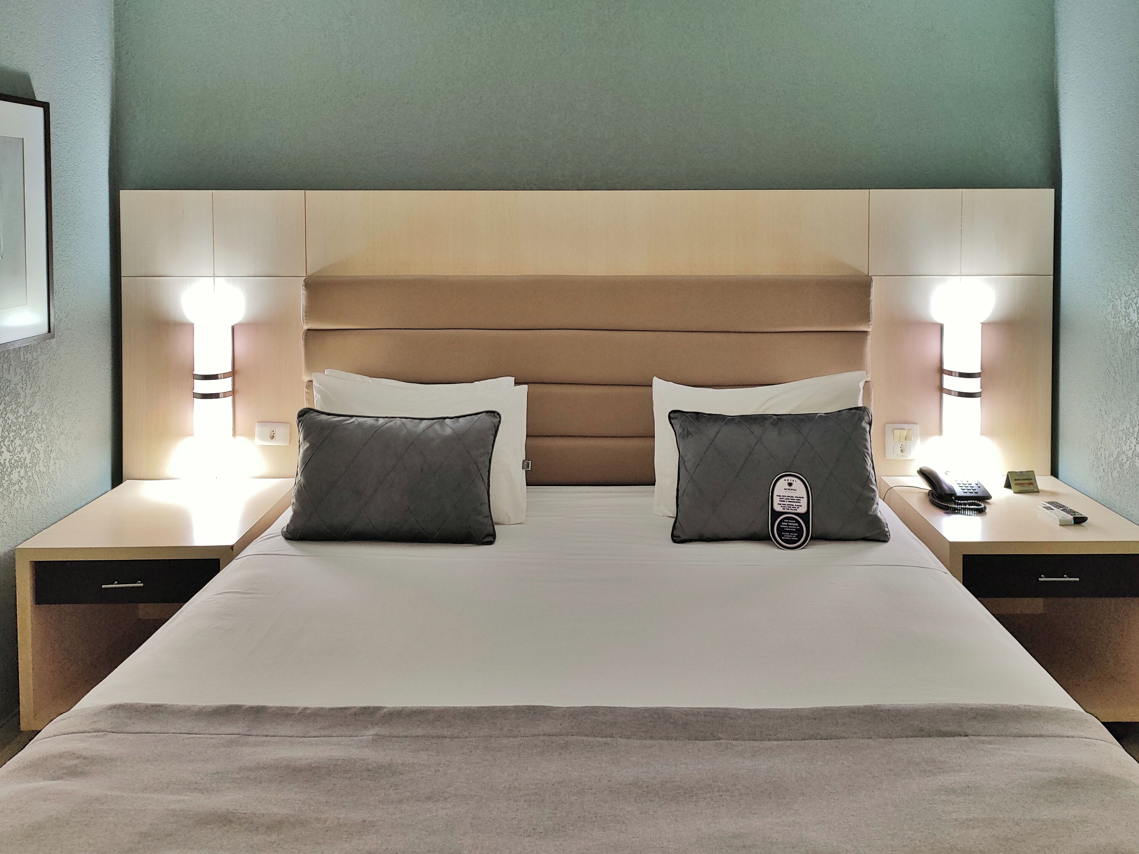 Una habitación de hotel con una cama grande, dos mesitas de noche y una lámpara de pared.
