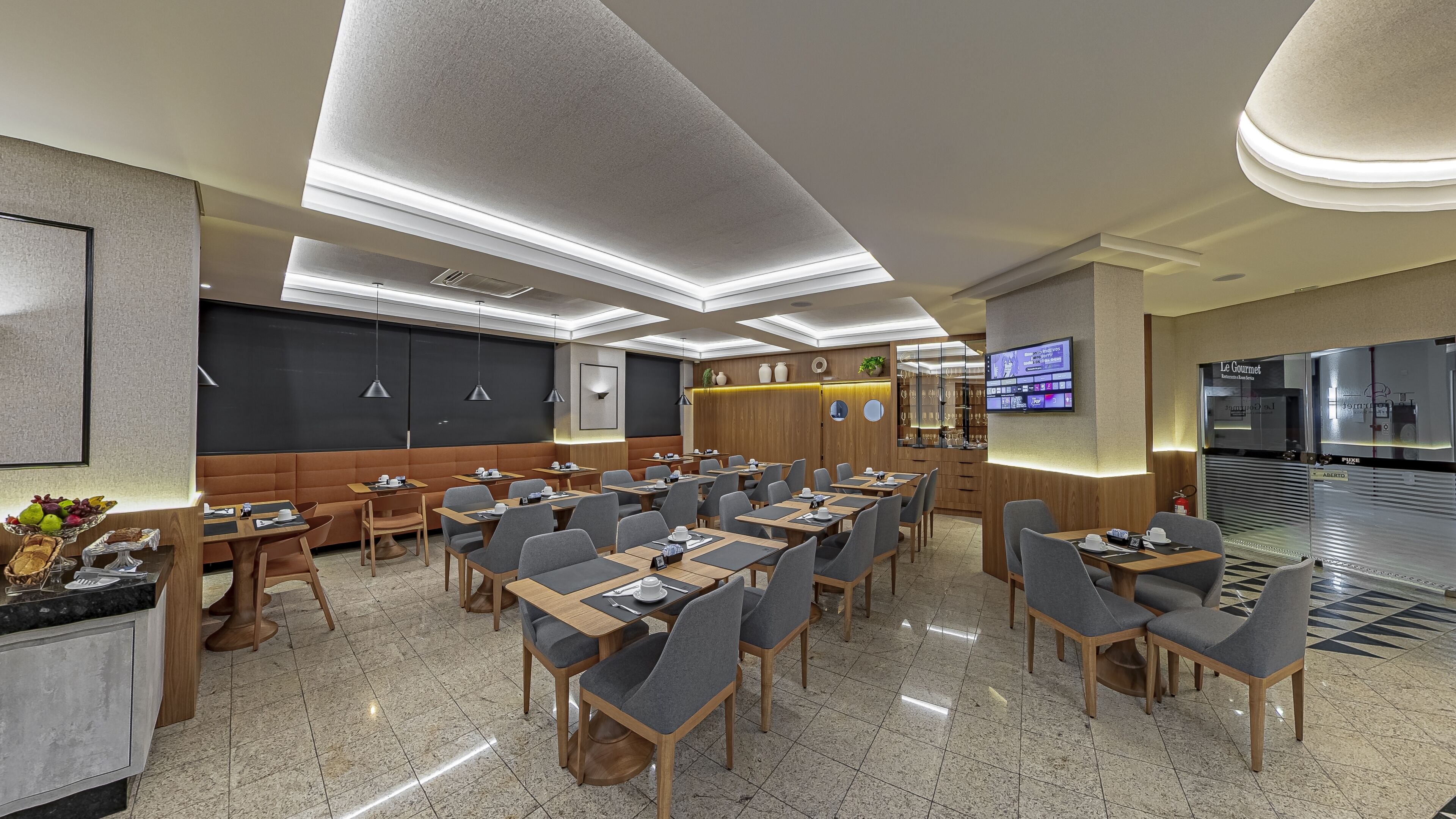 A modern conference room with a large screen, multiple tables, and a seating area.
