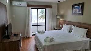 Een hotelkamer met een bed, een televisie, een bureau en een raam met gordijnen.