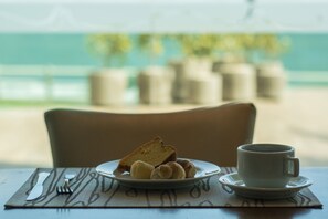 A table with a plate of croissants and a cup of coffee, set on a placemat. - Brisamar Hotel & SPA São Luís (São Luís)