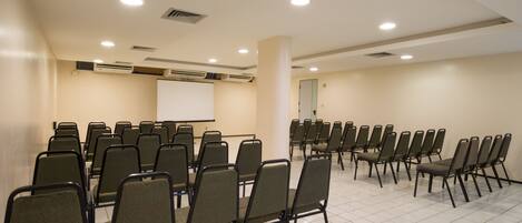 A conference room with rows of chairs, a whiteboard, and air conditioning units.