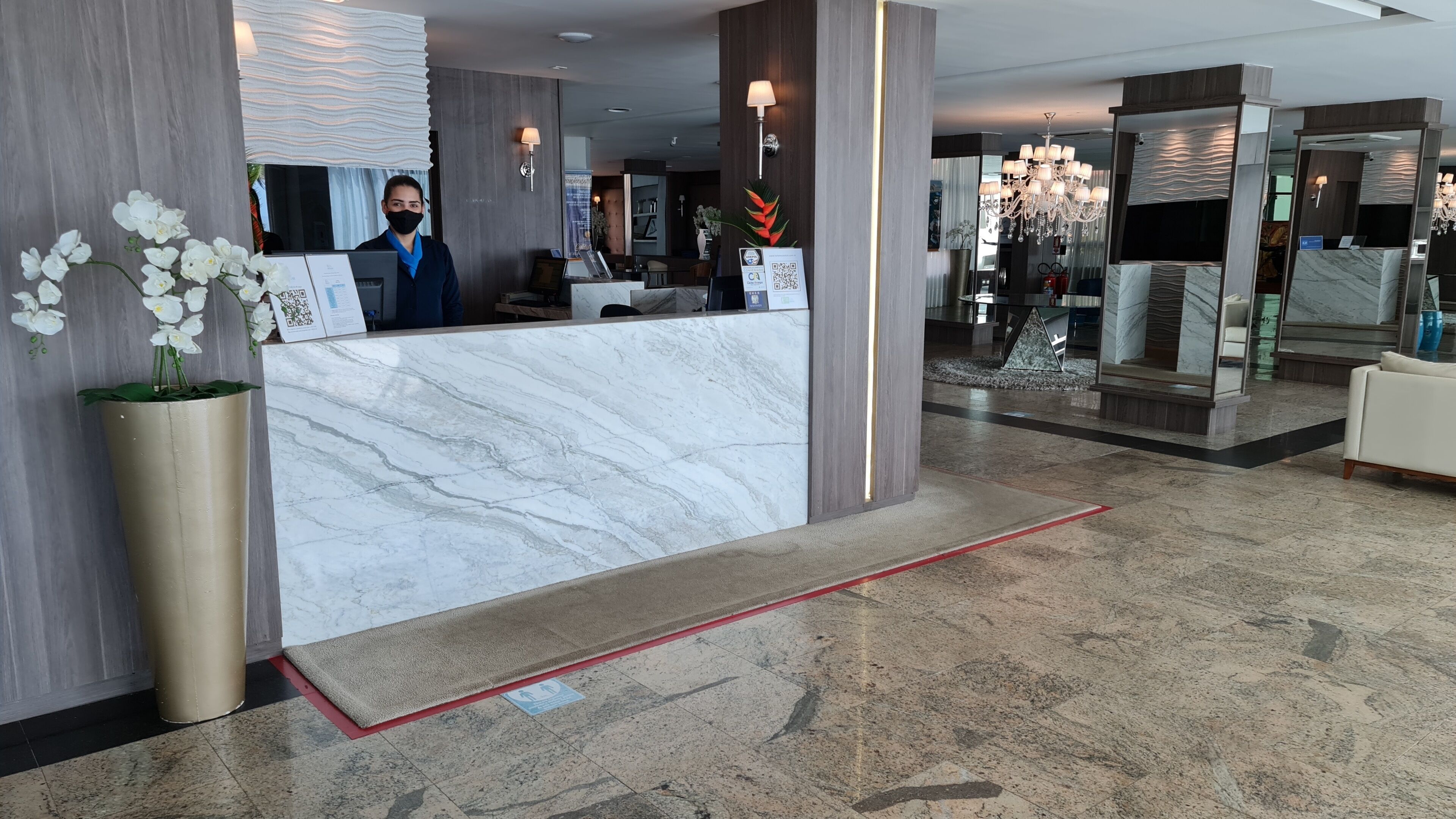 A hotel reception area with a marble counter, a receptionist, and a modern interior design.