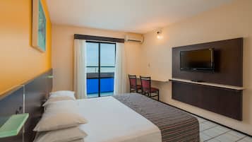 A hotel room with a bed, a TV mounted on the wall, a small table, and a chair.