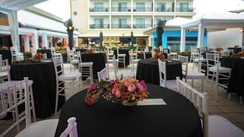 An outdoor dining area with round tables, white chairs, and floral centerpieces.