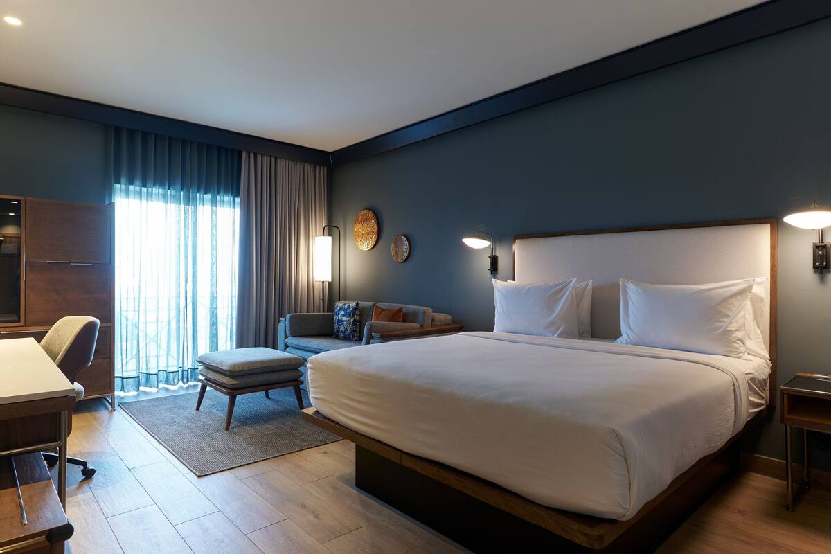 Una habitación de hotel moderna con una cama grande, un escritorio, una silla y un sofá.