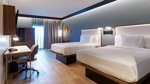 Une chambre d’hôtel avec deux lits, un bureau et une chaise.