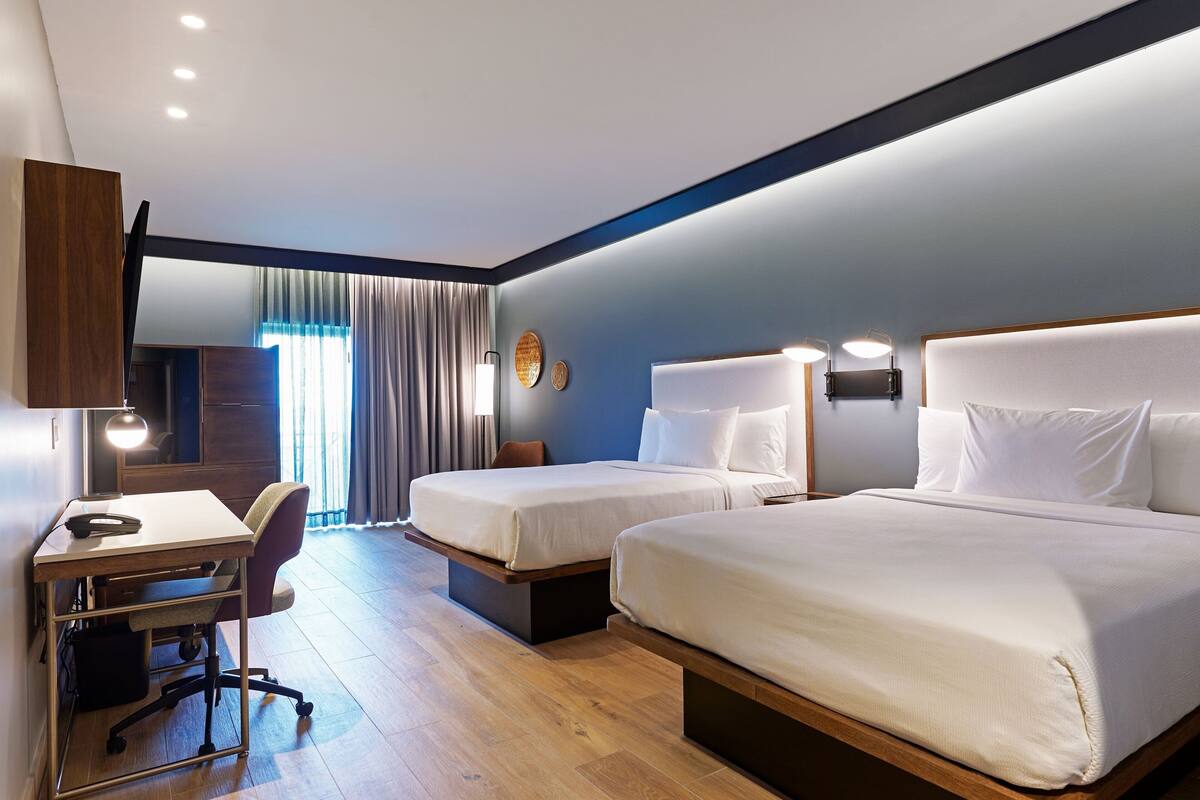Habitación de hotel con dos camas, un escritorio y una silla.