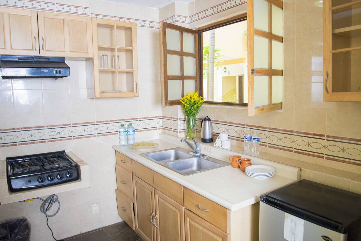 A kitchen with wooden cabinets, a gas stove, a sink, and a refrigerator.