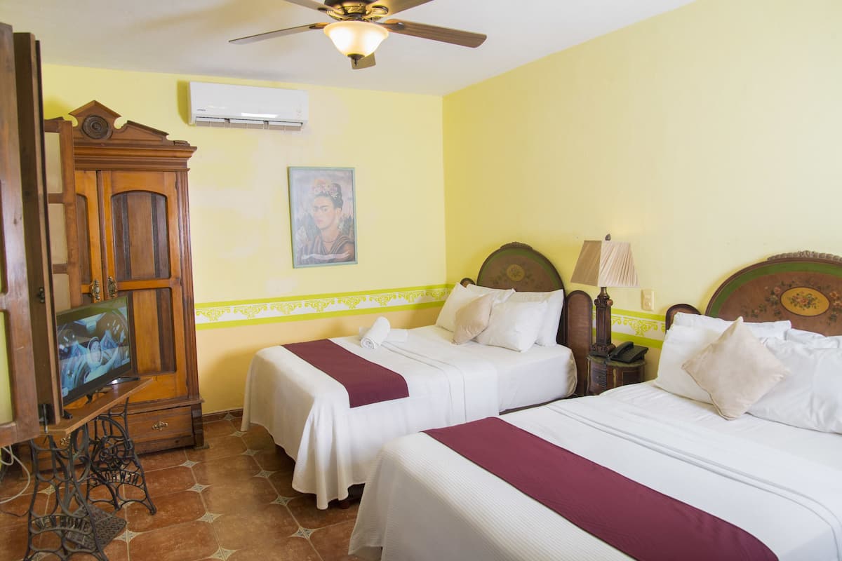 A hotel room with two beds, a wooden wardrobe, a television, and a ceiling fan.