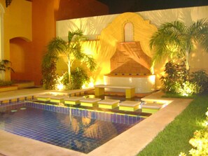 A swimming pool with multiple lanes, surrounded by palm trees and a decorative wall.