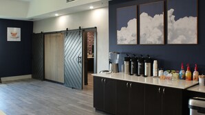 Cozinha moderna com porta deslizante, espaço para café e parede com quadros de arte com tema de nuvens.