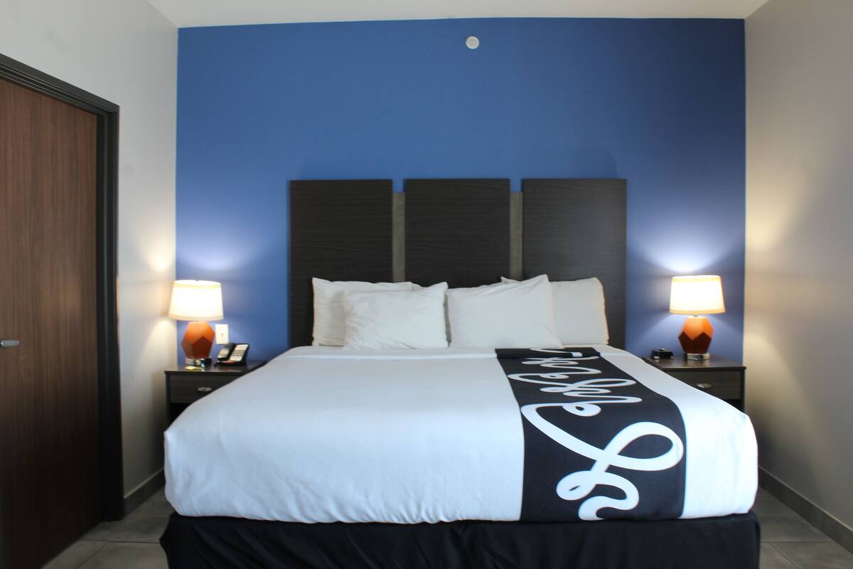 Ein Hotelzimmer mit einem großen Bett, zwei Nachttischen und einer blauen Akzentwand.